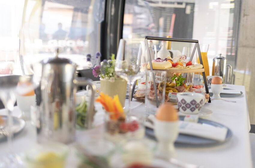 Richly set table with eggs, cheese, cold cuts, fruit and orange juice inside glass mountain gondola | © Großarler Bergbahnen GmbH & Co KG