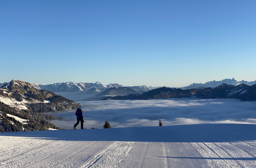 Person steht auf frisch präparierter Skipiste mit Blick auf Nebelmeer und Berge | © Großarler Bergbahnen GmbH & Co KG