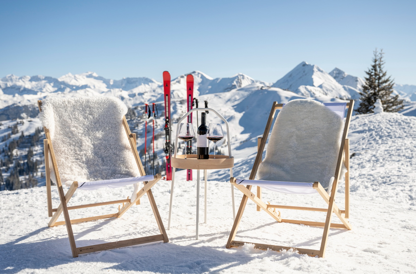 Zwei Liegestühle mit Decken stehen im Schnee, dazwischen Tisch mit Wein, Gläsern und Skiern vor Bergpanorama | © Großarler Bergbahnen GmbH & Co KG