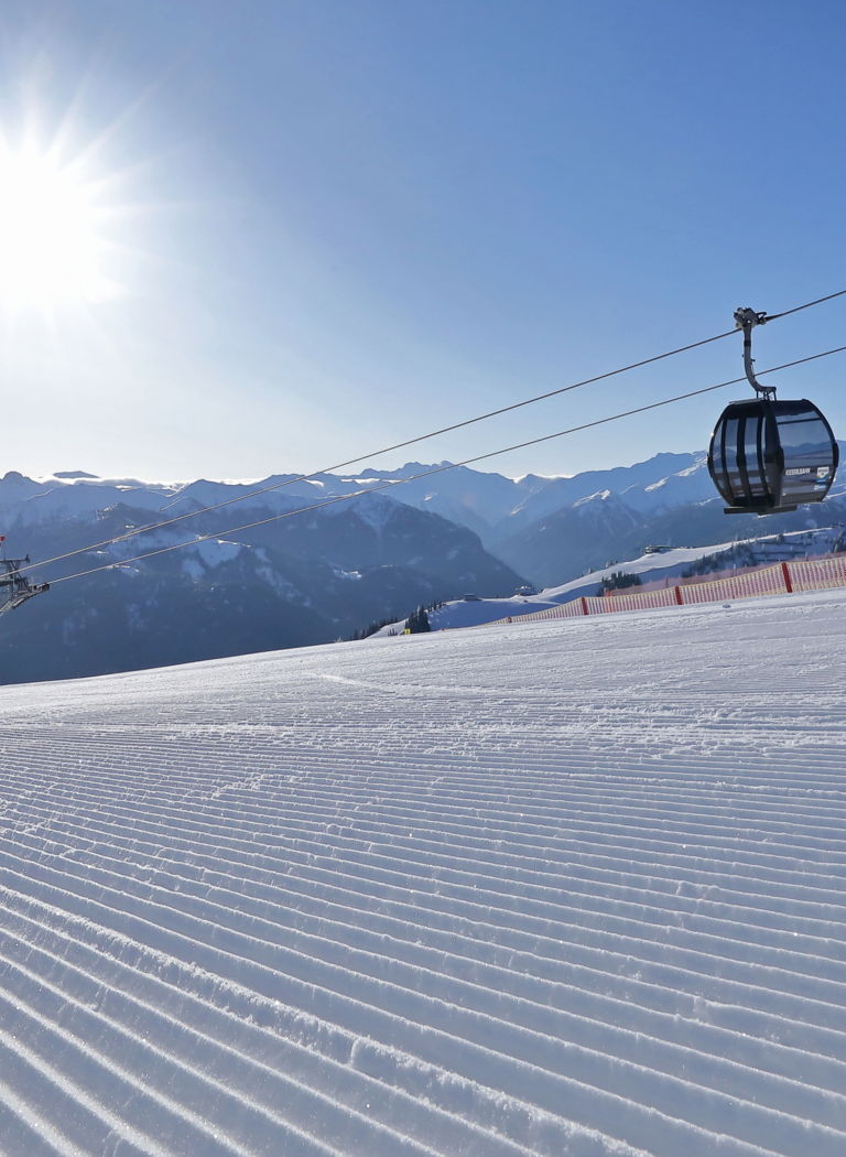 Single gondola over freshly groomed ski slope in Großarl with sunshine and mountain panorama | © Grossarler Bergbahnen GmbH & Co KG