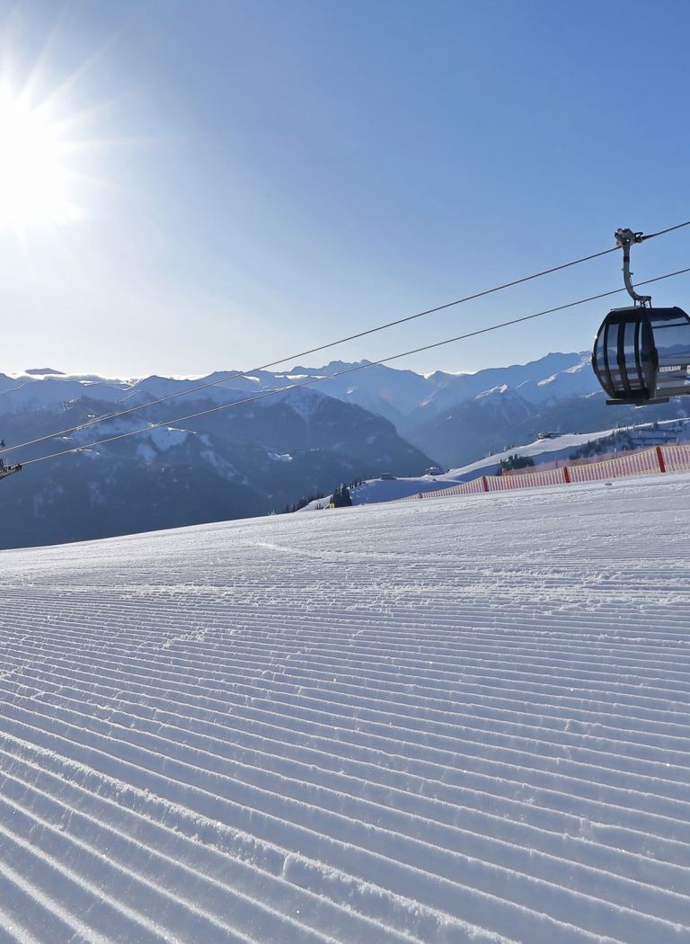 Sunny winter day with gondola and freshly groomed slope in Großarl | © Grossarler Bergbahnen GmbH & Co KG Single gondola over freshly groomed ski slope in Großarl with sunshine and mountain panorama | © Grossarler Bergbahnen GmbH & Co KG