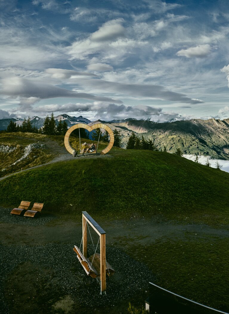 Wooden heart bench with alpine view and sea of clouds in the background | © Grossarler Bergbahnen GmbH & Co KG