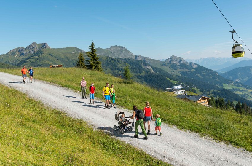 Families with kids and stroller on sunny alpine path in Großarl, yellow gondolas and panoramic valley view beside | © Grossarler Bergbahnen GmbH & Co KG