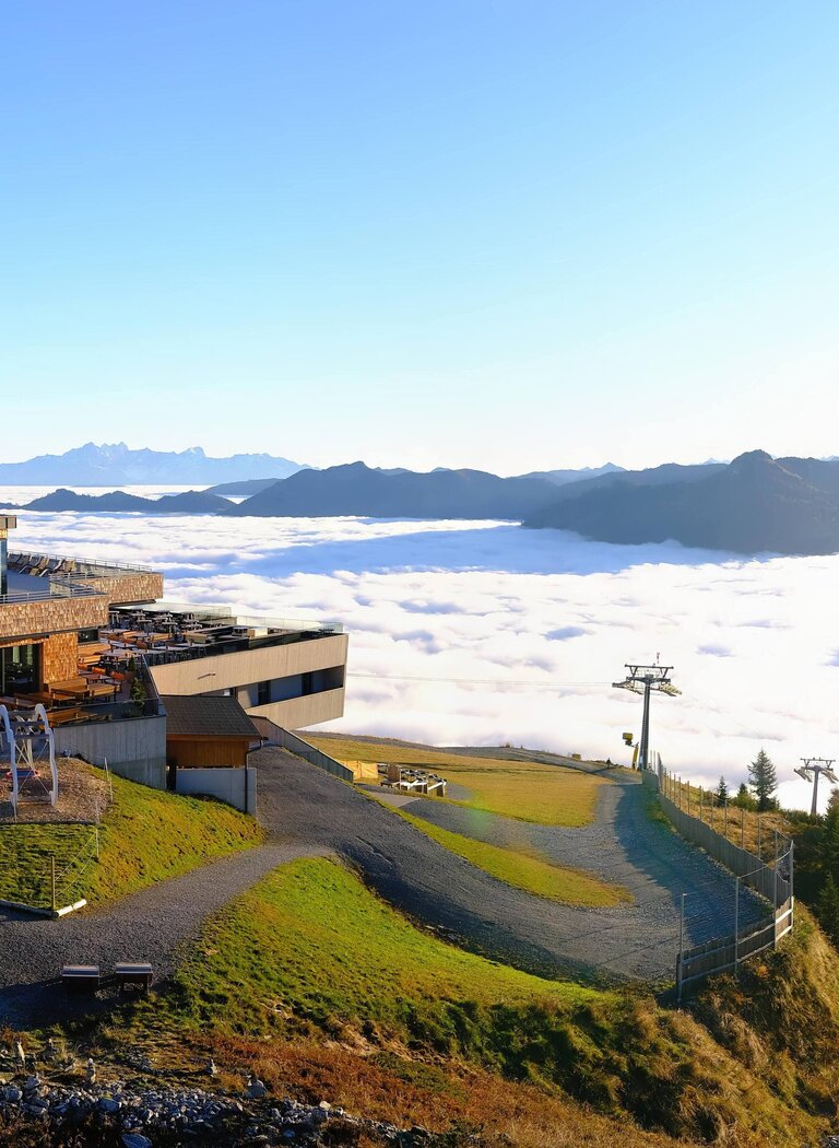 Kieserlbahn mountain station in Grossarl Valley above a dense sea of clouds with mountain peaks on the horizon. | © Grossarler Bergbahnen GmbH & Co KG