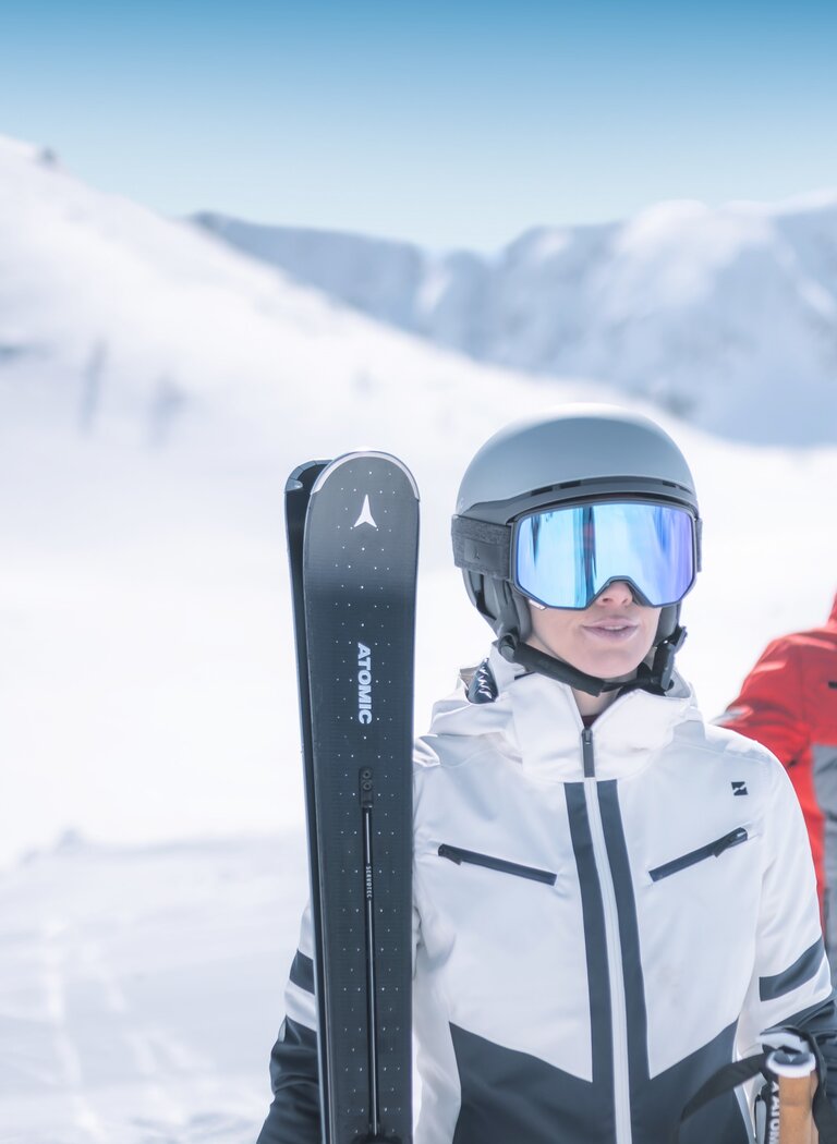 Zwei Skifahrer in moderner Ausrüstung stehen auf einer verschneiten Piste mit Helm und Skibrille, bereit für die Abfahrt. | © Ski amadé GmbH